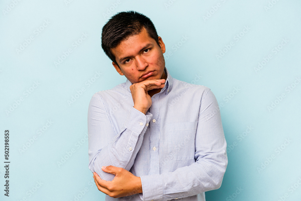 Young hispanic man isolated on blue background tired of a repetitive task. Young hispanic man isolated on blue background tired of a repetitive task.