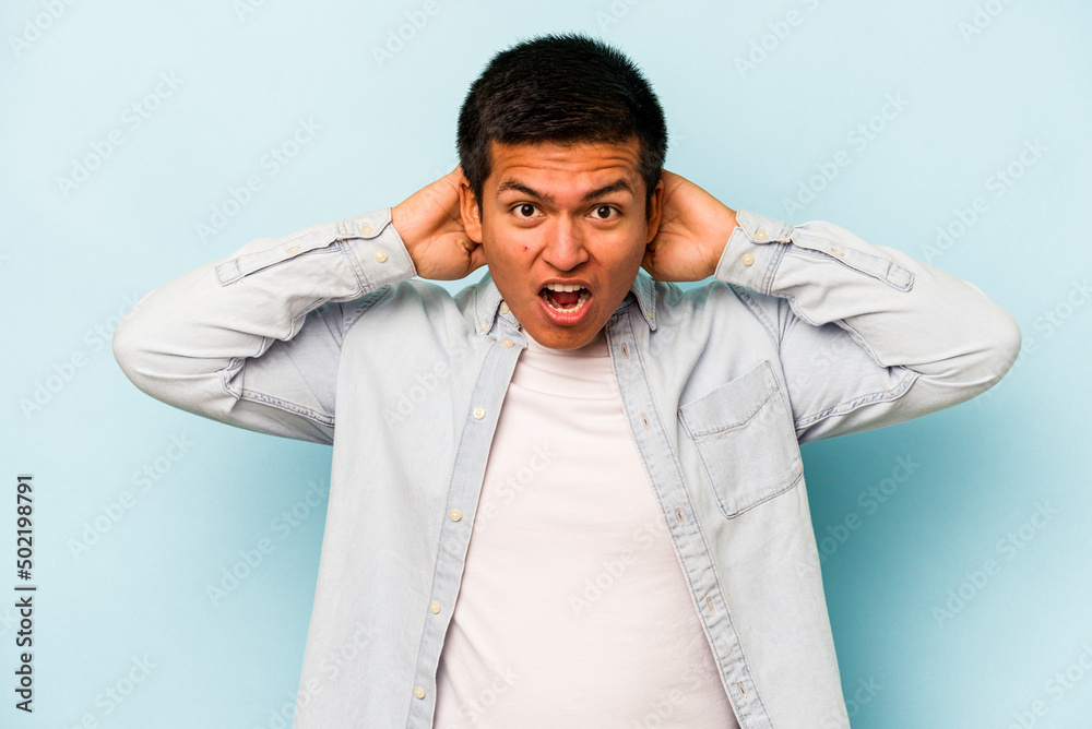 Young hispanic man isolated on blue background screaming, very excited, passionate, satisfied with something. Young hispanic man isolated on blue background screaming, very excited, passionate, satisfied with something.