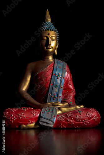 Sitting buddha statue in lotus position. The statue is in bright colors and inlaid with colored crystals.