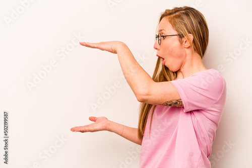 Young caucasian woman isolated on white background shocked and amazed holding a copy space between hands.