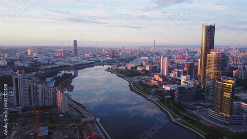 Beautiful panorama of modern city with reflection of sky in river at sunset. Stock footage. Modern city was painted pink by setting sun. High-rises reflect setting sun on background of pink city © Media Whale Stock