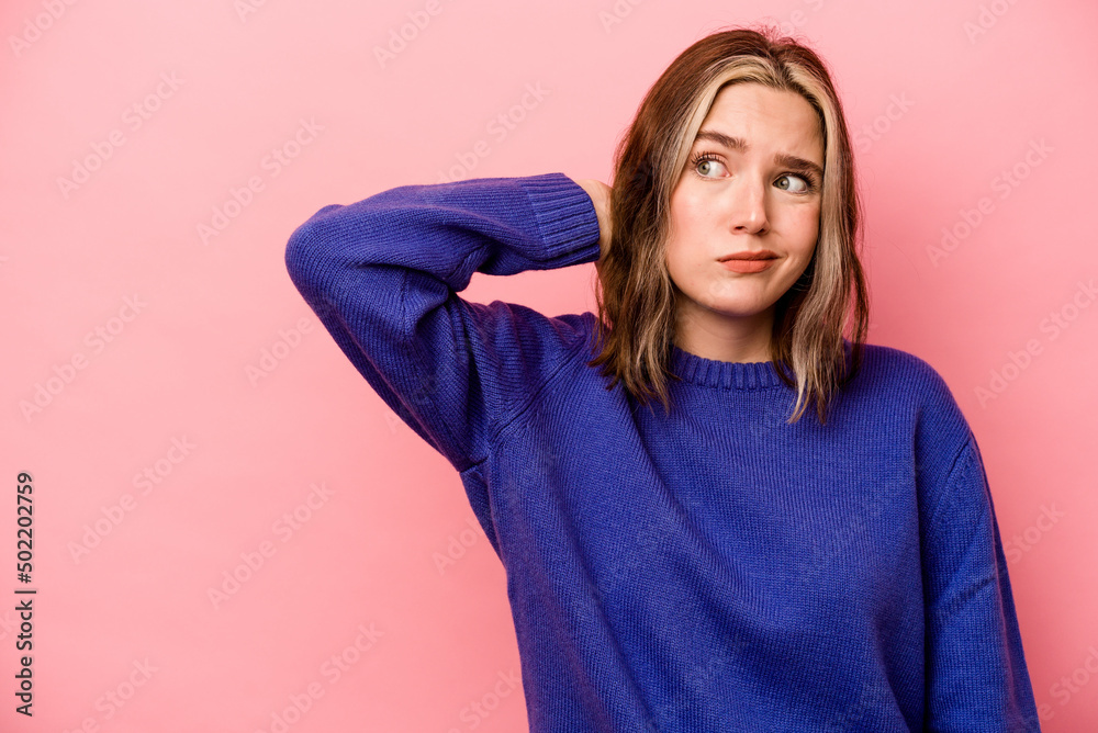 Fototapeta premium Young caucasian woman isolated on pink background touching back of head, thinking and making a choice.