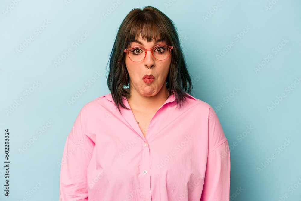 Fototapeta premium Young caucasian woman isolated on blue background shrugs shoulders and open eyes confused.