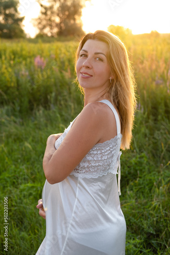 Outdoor pregnancy portrait: beautiful young pregnant female anticipate child, enjoy nature. Happy future mother expecting a baby soon