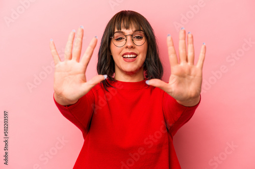 Young caucasian woman isolated on pink background showing number ten with hands.