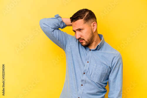 Young hispanic man isolated on yellow background tired and very sleepy keeping hand on head. © Asier