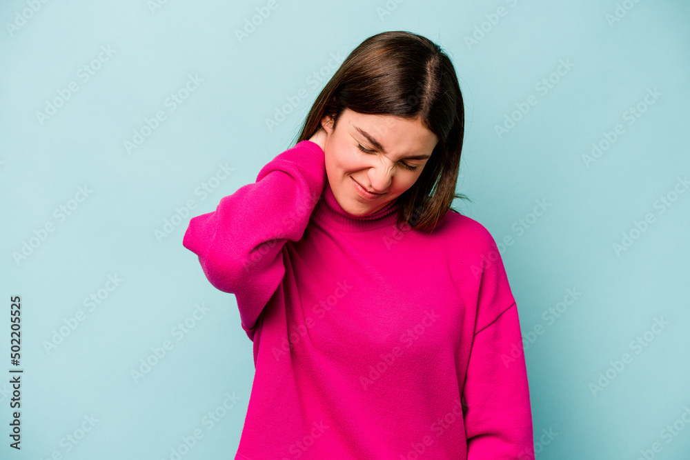 Fototapeta premium Young caucasian woman isolated on blue background suffering neck pain due to sedentary lifestyle.