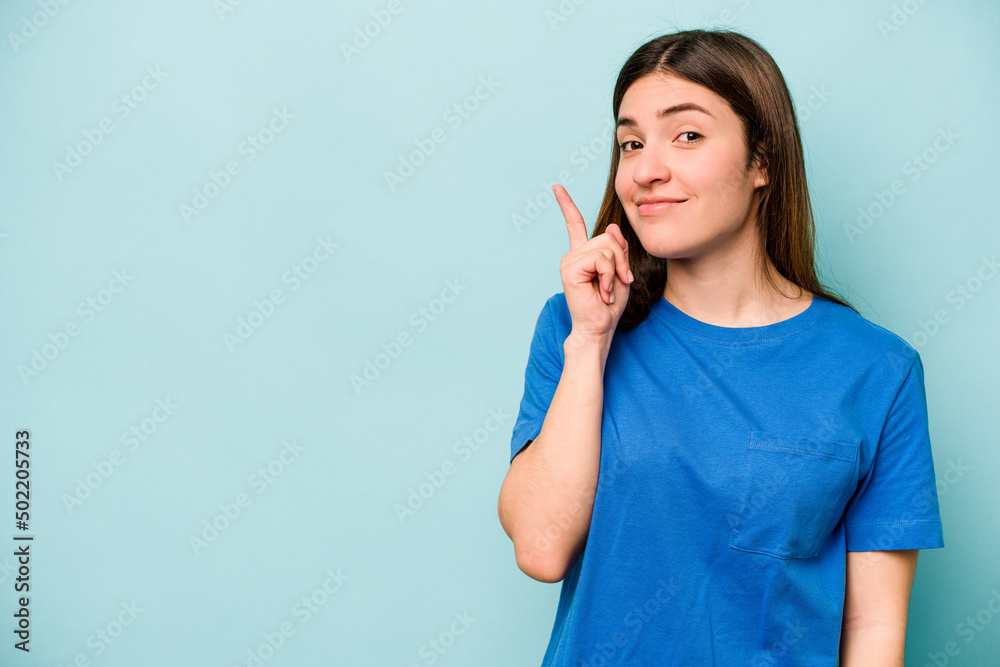 Young caucasian woman isolated on blue background showing number one with finger. Young caucasian woman isolated on blue background showing number one with finger.