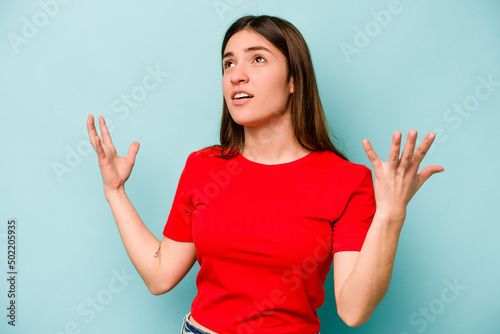 Young caucasian woman isolated on blue background screaming to the sky, looking up, frustrated. © Asier