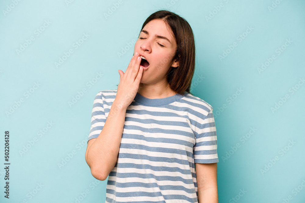 Young caucasian woman isolated on blue background yawning showing a tired gesture covering mouth with hand. Young caucasian woman isolated on blue background yawning showing a tired gesture covering mouth with hand.