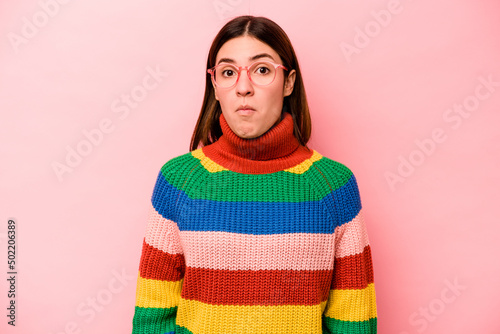 Young caucasian woman isolated on pink background shrugs shoulders and open eyes confused.