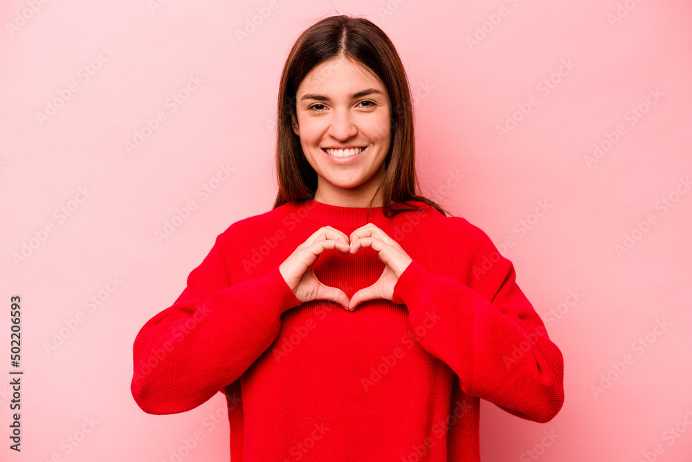 Young caucasian woman isolated on pink background smiling and showing a heart shape with hands. Young caucasian woman isolated on pink background smiling and showing a heart shape with hands.