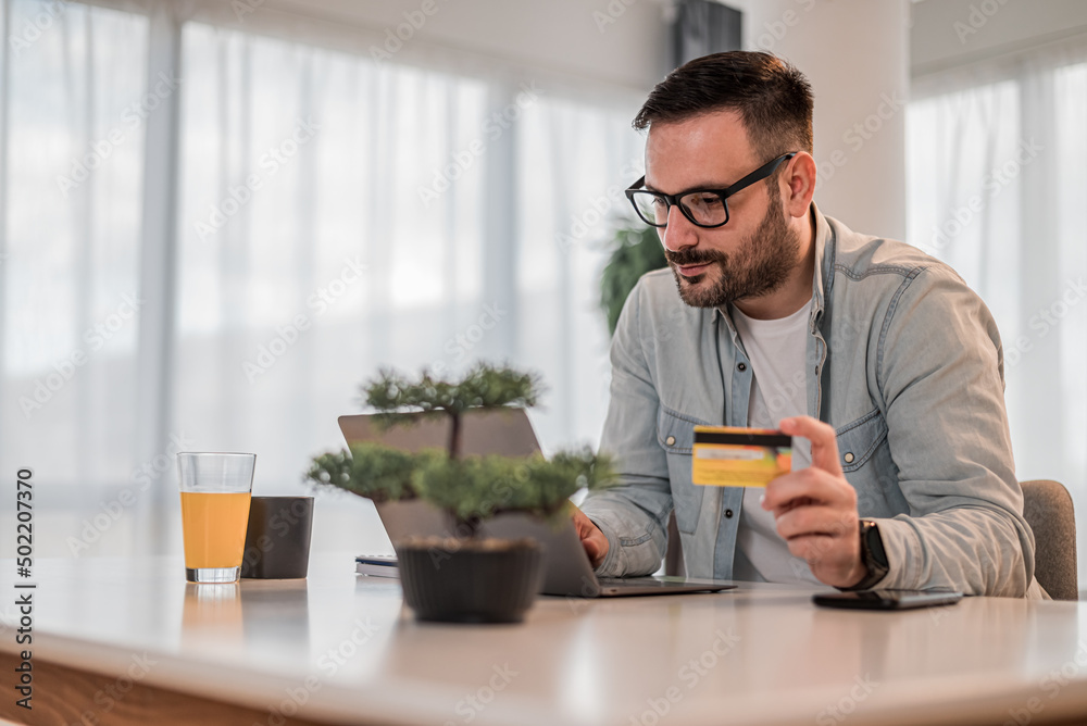 Businessman doing online transaction from laptop with credit card at office desk Businessman doing online transaction from laptop with credit card at office desk