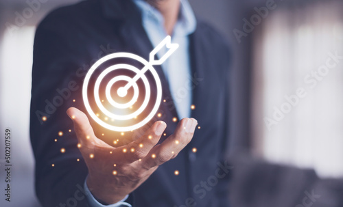 Man holding virtual dartboard and arrow with copy space for setup business objective target concept. photo