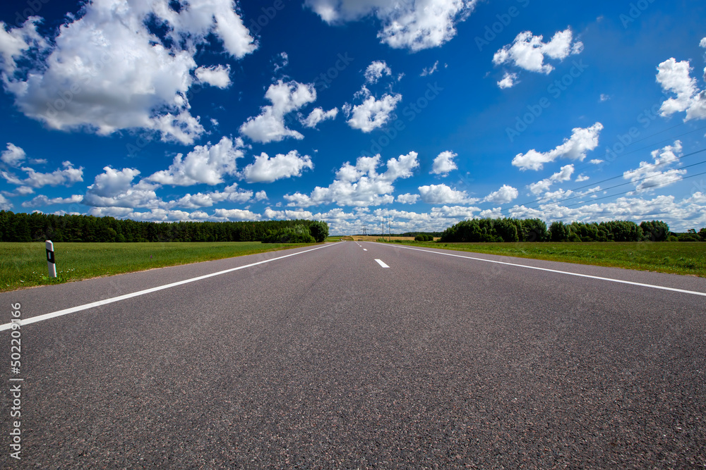 paved highway with blue sky and clouds