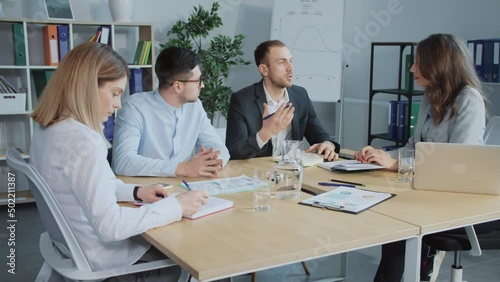 Man speaking and gesticulating actively. View of business people in suits sitting at table. People actively communicating. Representatives of two companies agreed to cooperate, shaking hands