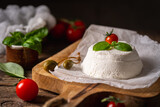 Homemade Italian ricotta cheese or cottage cheese with basil ready to eat. Vegetarian healthy, nutritious diet food on wooden background