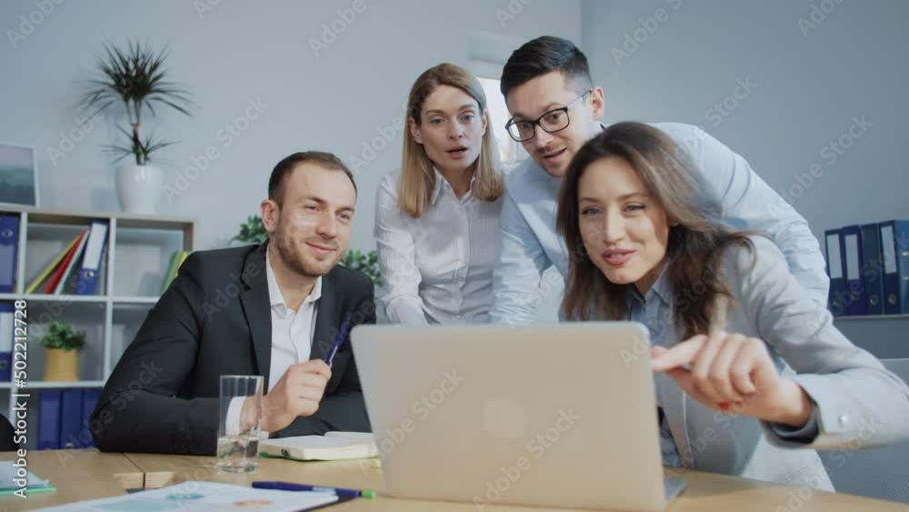 Four colleagues looking at laptop screen, waiting for important news. Happy colleagues receiving information about successful transaction. Office workers giving five to each other. Daytime. Good end Four colleagues looking at laptop screen, waiting for important news. Happy colleagues receiving information about successful transaction. Office workers giving five to each other. Daytime. Good end