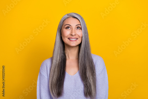 Photo of pretty cute retired woman wear blue sweater looking empty space isolated yellow color background