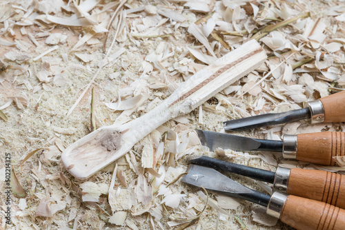 Selbst geschnitzter Holzlöffel Kochlöffel Pfannenkratzer Gabel bearbeitet mit Messer Werkzeug auf einer Werkbank mit Holzspäne, Deutschland photo