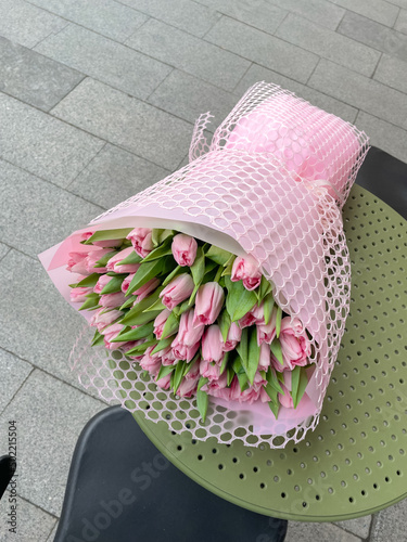 Big Spring bouquet of pink tulipsin pink wrapping laying on cafe table. photo