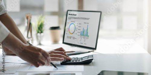 Businessmen use a calculator to calculate company financial statements for their colleagues, view and jointly solve problems within the company. Business finance and accounting concepts