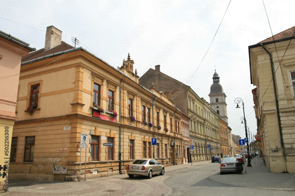 Old two-storey Eastern European building on the street with street signs and with a church bell tower