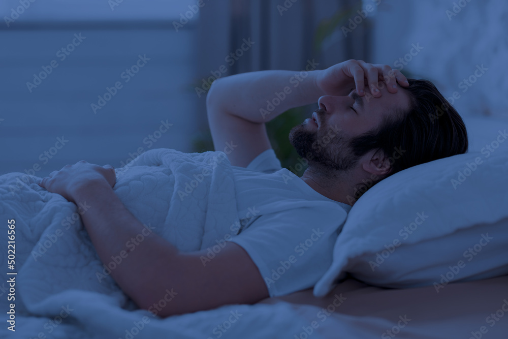 Sleepless man laying in bed alone at night Sleepless man laying in bed alone at night