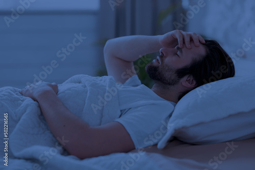 Sleepless man laying in bed alone at night