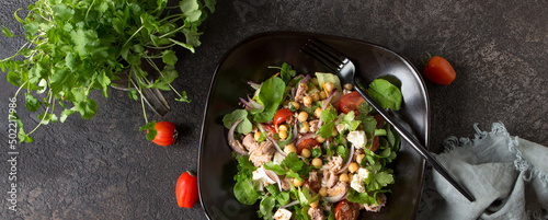 plate with salad with tuna, chickpeas and feta on a dark table