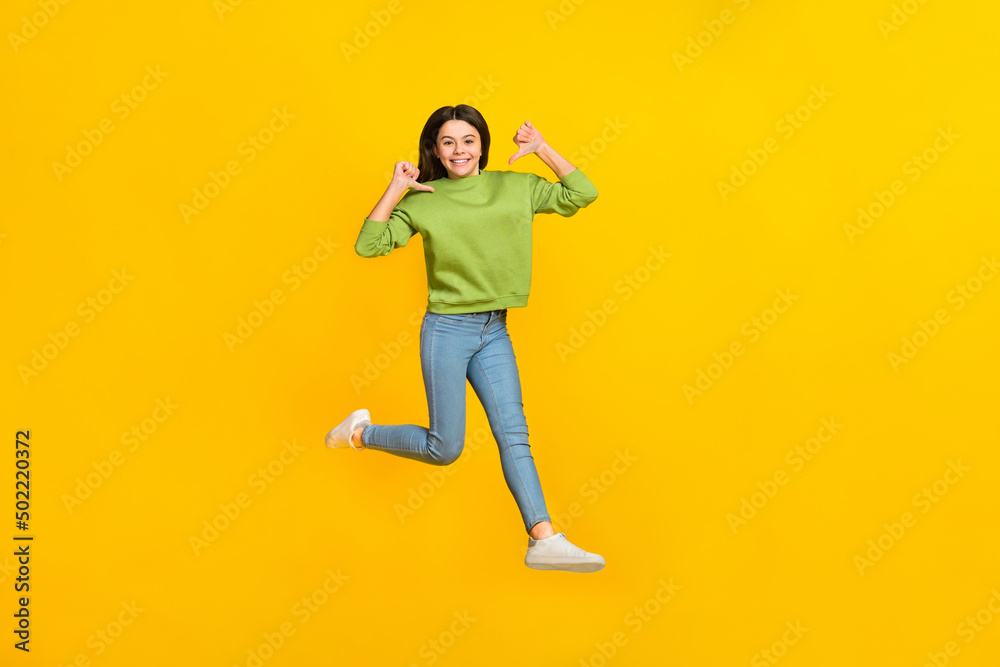 Full size photo of young excited girl jump up indicate fingers herself choice isolated over yellow color background