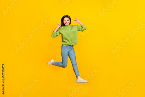 Full size photo of young excited girl jump up indicate fingers herself choice isolated over yellow color background
