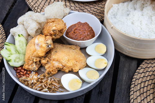 Nasi lemak with fried chicken, anchovis, eggs, groundnuts and sambal is popular Malaysia delicacy, served with rice cooked in coconut milk photo