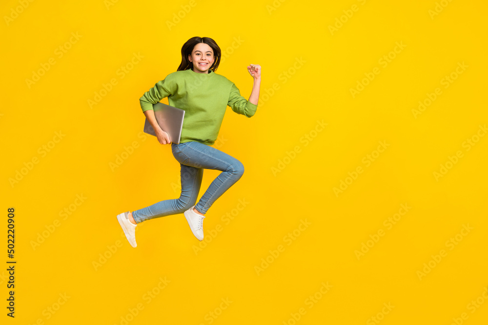 Full length photo of young girl active jumper rush hold laptop isolated over yellow color background