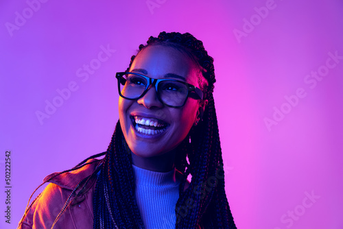 Portrait of female fashion model in cotton shirt isolated on purple background in neon light. Concept of beauty, art, fashion, youth and emotions