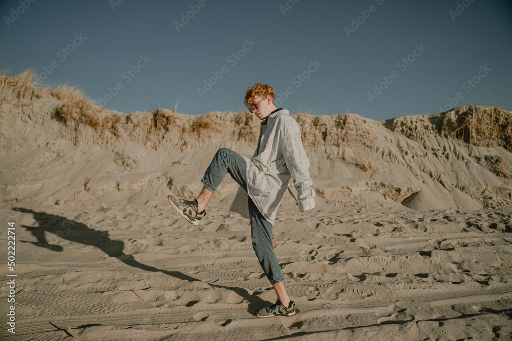 an unusual young man walks on the sand with long steps