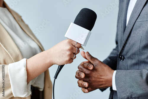 Side view closeup of young woman holding microphone while interviewing business expert