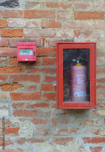 Feueralarm und Feuerlöscher in einem Kasten an einer verwitterten Wand