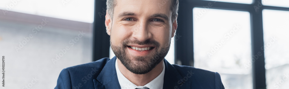 Obraz premium cheerful bearded businessman smiling at camera in office, banner.