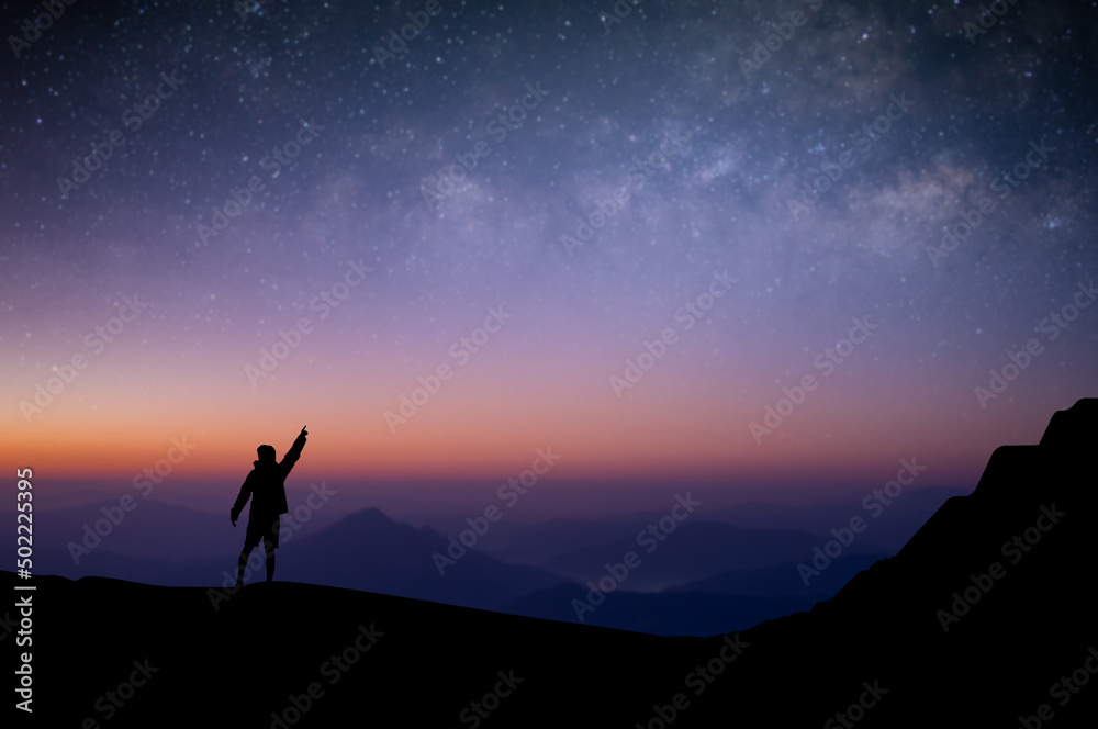 Silhouette of young traveler and backpacker standing and open arms watched the star and milky way alone on top of the mountain. He enjoyed traveling and was successful when he reached the summit.