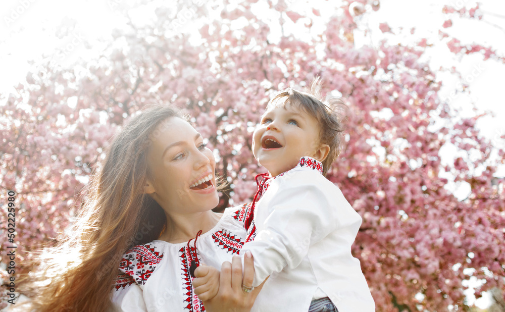 Obraz premium Pretty woman and child in the blooming spring garden. Mothers day holiday concept