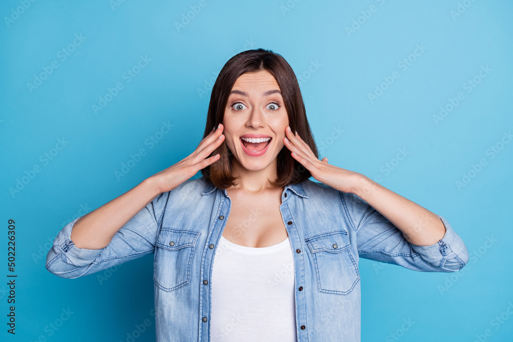 Photo of impressed adorable lady dressed denim shirt arms cheeks smiling isolated blue color background Photo of impressed adorable lady dressed denim shirt arms cheeks smiling isolated blue color background