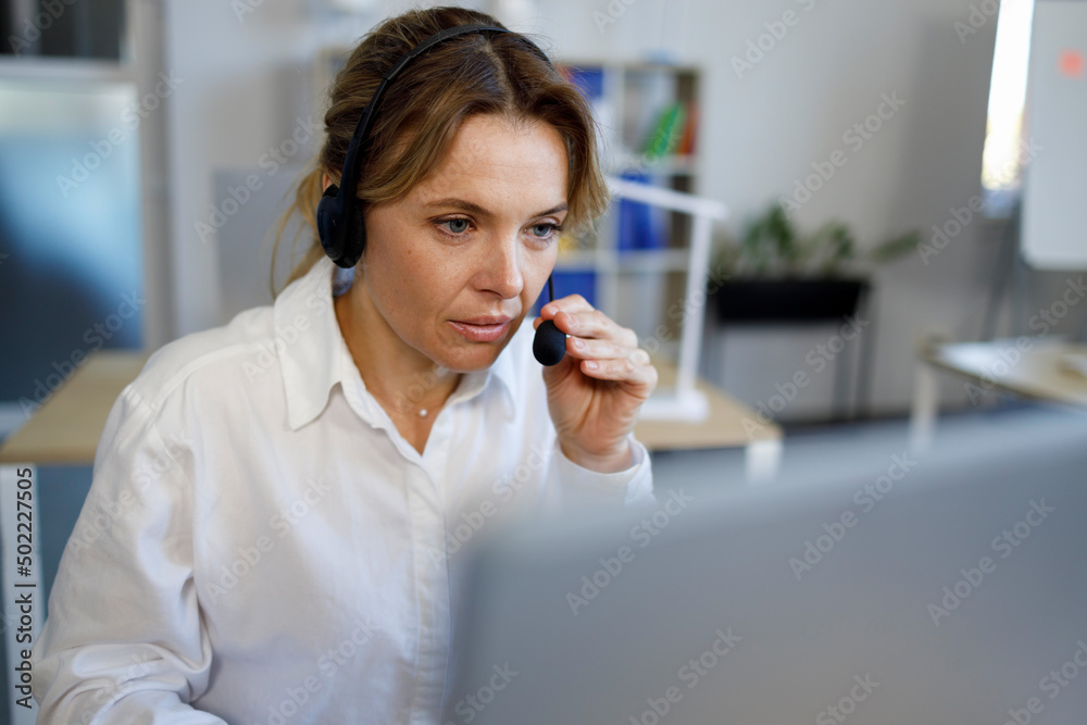 Female call center agent with a headset works on the support hotline Female call center agent with a headset works on the support hotline