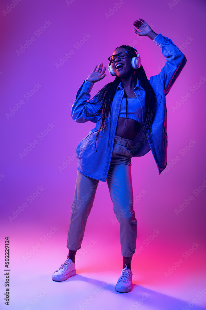 Monochrome portrait of young attractive happy woman in casual style outfit dancing isolated on very peri color background. Concept of fashion, youth, style Monochrome portrait of young attractive happy woman in casual style outfit dancing isolated on very peri color background. Concept of fashion, youth, style