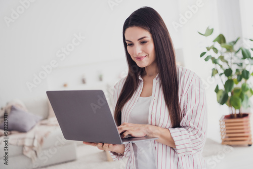 Portrait of attractive focused skilled long-haired woman using laptop developing web finance project at home indoors © deagreez