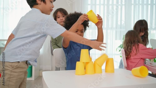 African American play stacking cup in the kindergarten classroom and naughty boy try falling cup stacking. Africa boy feeling angry and upset. Education and learning concept. Lifestyle in school