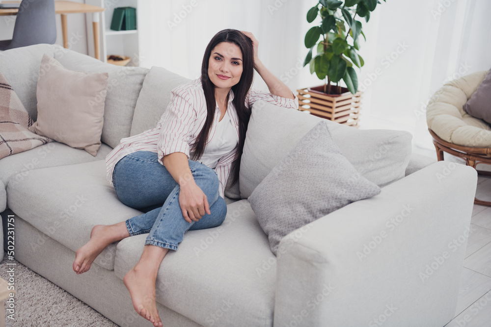 Portrait of attractive cheerful calm healthy long-haired woman sitting on divan enjoying day off at home indoors Portrait of attractive cheerful calm healthy long-haired woman sitting on divan enjoying day off at home indoors