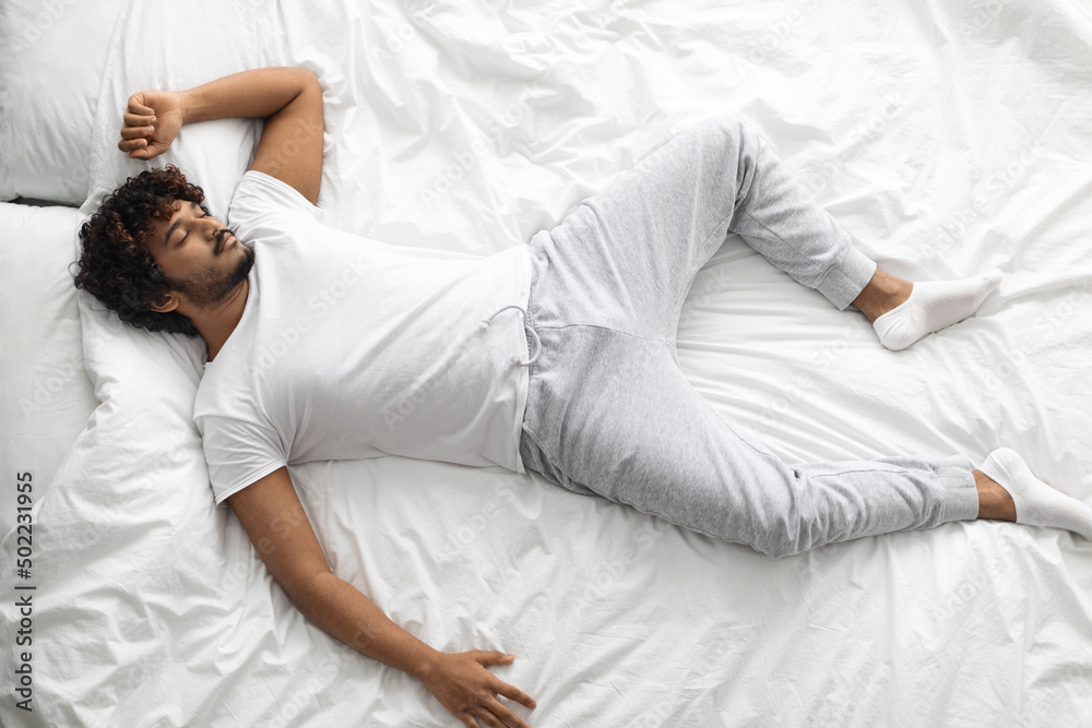 Top view of eastern guy sleeping alone in bed Top view of eastern guy sleeping alone in bed