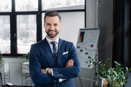 Ταπετσαρία happy brunette economist in blazer standing with crossed arms and smiling at camera