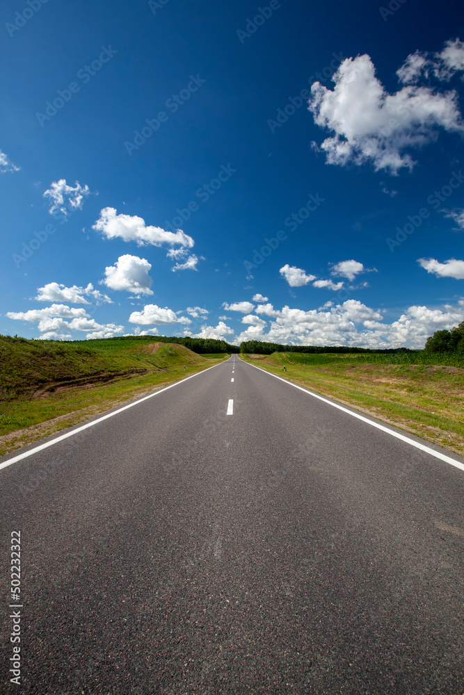 paved highway with blue sky and clouds